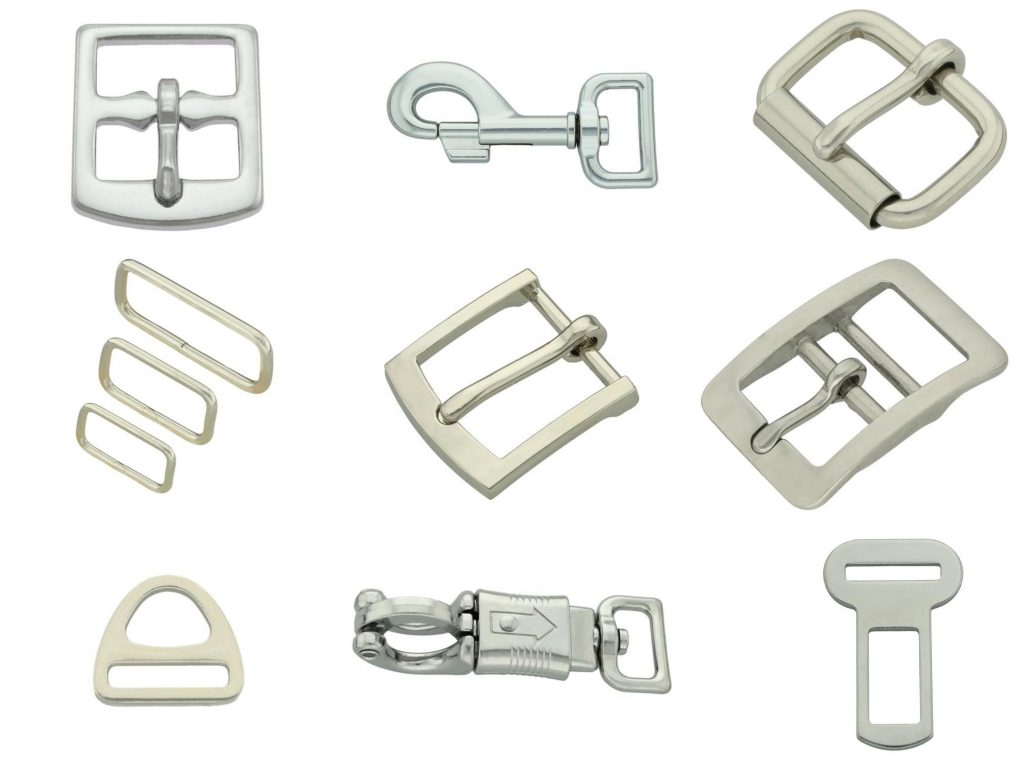 Ensemble de boucles, crochets, mousquetons et anneaux métalliques pour la fabrication d'accessoires pour animaux, disposés sur fond blanc.
